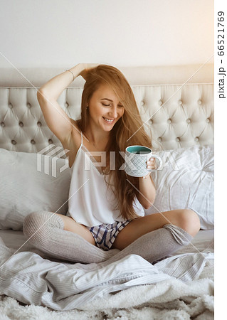 Home self isolation, bedtime. People adaptation during covid-19 pandemic quarantine. Girl woomen in bed, drinking coffee and smiling Home self isolation, bedtime. People adaptation during covid-19 pandemic quarantine. Girl woomen in bed, drinking coffee and smiling 66521769