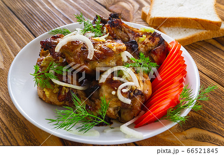 Closeup fried chicken wings, with fresh tomatoes, onions, dill, garlic and bread on a wooden background. The concept of meat food. 66521845