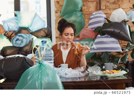 Upset female sitting at table among scraps and garbage 66521975