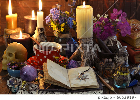 Still life with cup of tea, burning candles, open diary with copy space and crystal on witch table. Esoteric, wicca and occult background with magic objects, fortune telling and divination ritual Still life with cup of tea, burning candles, open diary with copy space and crystal on witch table. Esoteric, wicca and occult background with magic objects, fortune telling and divination ritual 66529197