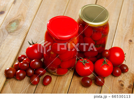 Glass jar with pickled red tomatoes and fresh tomatoes 66530113