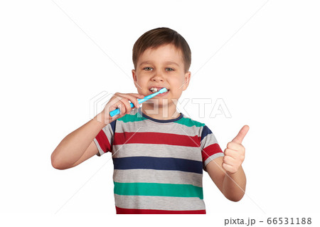 Smiling boy brushes his teeth and shows a thumbs up, isolated on a white background 66531188