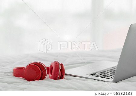 Red modern headphones and laptop computer on white bedsheet. Red modern headphones and laptop computer on white bedsheet. 66532133