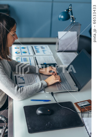 Business woman sitting at her desk working on laptop in office. 66533433