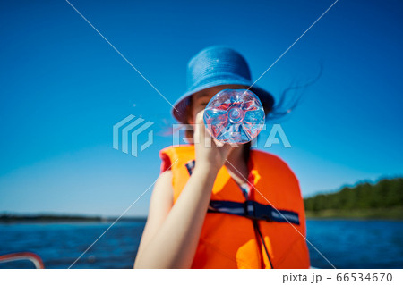 blurry little girl hides her mouth behind a bottle on a motorboat 66534670