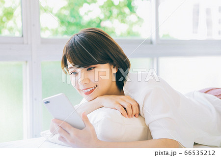 寝転がってスマホを見る女性(※婚活、結婚相談所等のサイトやアプリなどでのご利用はお控え下さい) 寝転がってスマホを見る女性(※婚活、結婚相談所等のサイトやアプリなどでのご利用はお控え下さい) 66535212