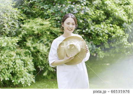 庭で麦わら帽子を持つ若い女性［夏のイメージ］の写真素材 [66535976 ...
