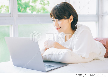 寝転がってパソコンを使う女性 婚活 結婚相談所等のサイトやアプリなどでのご利用はお控え下さい の写真素材