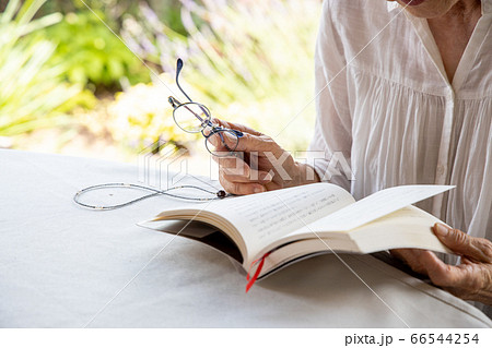 老眼鏡をもって読書しようとしている高齢女性 66544254