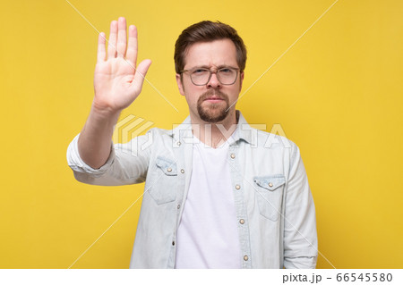 Serious caucasian man holding up hand. Serious caucasian man holding up hand. 66545580