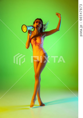 Beautiful girl in fashionable swimsuit isolated on gradient studio background in neon light. Summer, resort, fashion and weekend concept Beautiful girl in fashionable swimsuit isolated on gradient studio background in neon light. Summer, resort, fashion and weekend concept 66547873
