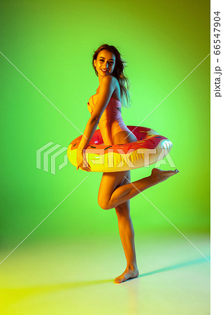 Beautiful girl in fashionable swimsuit isolated on gradient studio background in neon light. Summer, resort, fashion and weekend concept Beautiful girl in fashionable swimsuit isolated on gradient studio background in neon light. Summer, resort, fashion and weekend concept 66547904