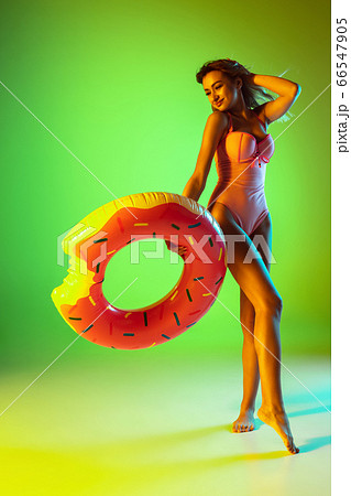 Beautiful girl in fashionable swimsuit isolated on gradient studio background in neon light. Summer, resort, fashion and weekend concept Beautiful girl in fashionable swimsuit isolated on gradient studio background in neon light. Summer, resort, fashion and weekend concept 66547905