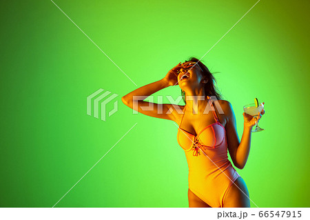 Beautiful girl in fashionable swimsuit isolated on gradient studio background in neon light. Summer, resort, fashion and weekend concept Beautiful girl in fashionable swimsuit isolated on gradient studio background in neon light. Summer, resort, fashion and weekend concept 66547915