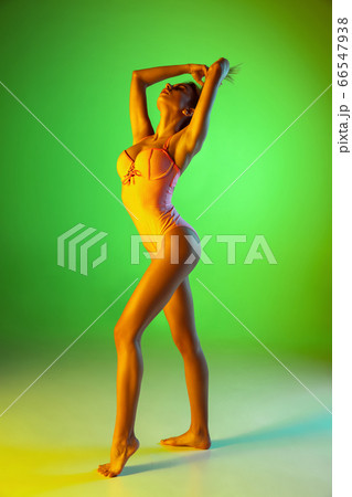 Beautiful girl in fashionable swimsuit isolated on gradient studio background in neon light. Summer, resort, fashion and weekend concept 66547938