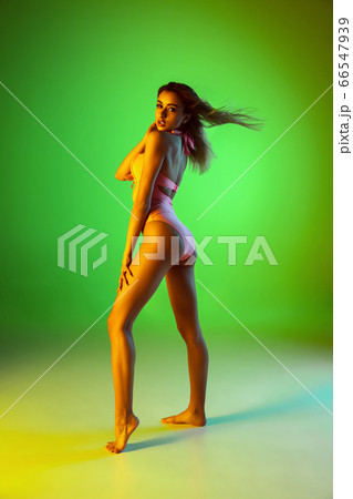Beautiful girl in fashionable swimsuit isolated on gradient studio background in neon light. Summer, resort, fashion and weekend concept 66547939