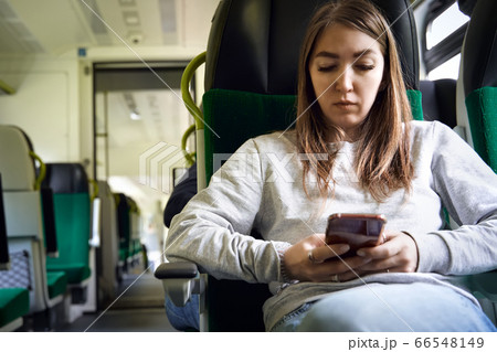 Young woman using smartphone in a train. 66548149