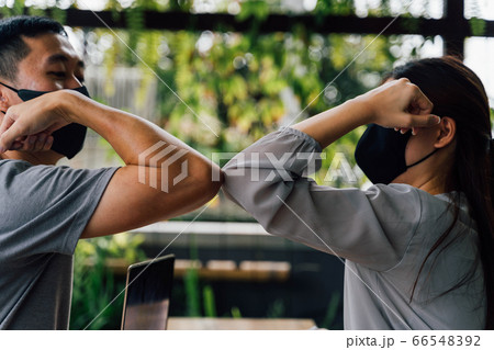 Asian woman and man friends wearing face mask outdoors. Friends greeting and shaking with elbows as new normal. Corona Virus - Covid 19 elbow bumps greeting style to prevent contact and virus spread 66548392