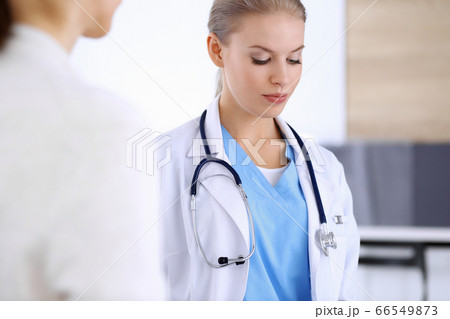 Doctor and patient during consultation. Physician at work filling up medication history record while sitting in emergency hospital, portrait shoot. Medicine and health care concept Doctor and patient during consultation. Physician at work filling up medication history record while sitting in emergency hospital, portrait shoot. Medicine and health care concept 66549873