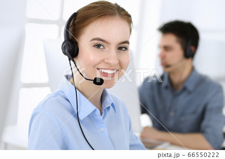 Group of operators at work. Call center. Focus on beautiful woman receptionist in headset at customer service. Business concept and casual clothing style Group of operators at work. Call center. Focus on beautiful woman receptionist in headset at customer service. Business concept and casual clothing style 66550222