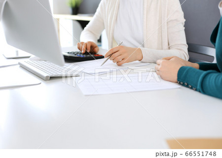 Accountant checking financial statement or counting by calculator income for tax form, hands close-up. Business woman sitting and working with colleague at the desk in office. Audit concept Accountant checking financial statement or counting by calculator income for tax form, hands close-up. Business woman sitting and working with colleague at the desk in office. Audit concept 66551748