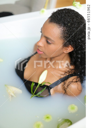 Portrait of black girl taking milk bath and wearing swimsuit. 66551962