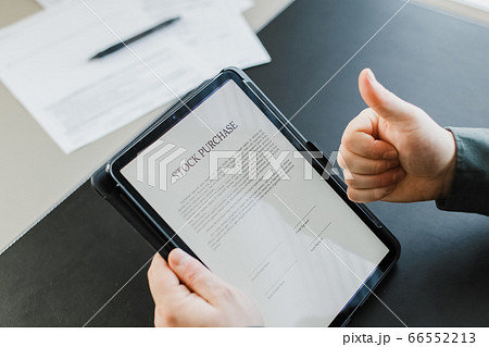 Man reading stock purchase agreement on tablet and showing thumbs up. Man reading stock purchase agreement on tablet and showing thumbs up. 66552213