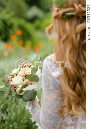 Back view portrait of young bride with bouquet walking in field. Back view portrait of young bride with bouquet walking in field. 66552526
