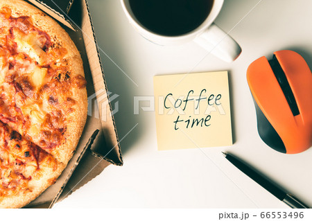 Pizza in box, cup of coffee, laptop, computer mouse, pen and sticker with text COFFEE TIME on table in office. 66553496