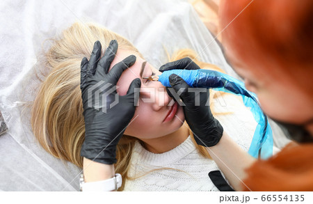 Girl lies in salon on procedure permanent eyebrow Girl lies in salon on procedure permanent eyebrow 66554135
