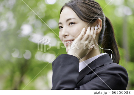 通勤時にブルートゥースイヤホンで音楽を聴く若いビジネスウーマン  66556088