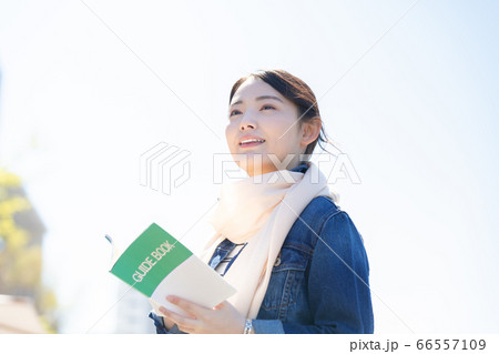 ライフスタイル　ガイドブックを持って歩く女性 66557109