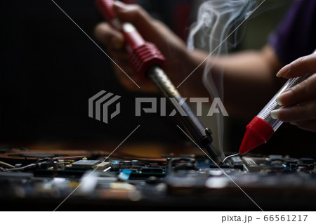 Close-up hand technician repairing broken laptop notebook computer with electric soldering Iron 66561217
