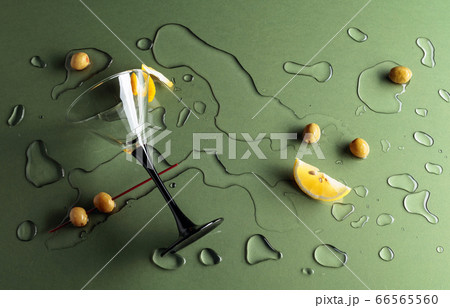 Glass of martini with green olives and lemon on a 66565560