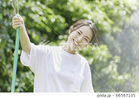 庭にホースで水をまく若い女性 夏のイメージ の写真素材 庭にホースで水をまく若い女性 夏のイメージ の写真素材