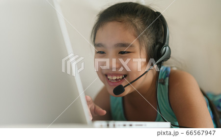 asian girl student wear headphone studying homework during online lesson at home 66567947
