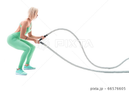 Woman doing exercises with battle rope. Woman doing exercises with battle rope. 66576605