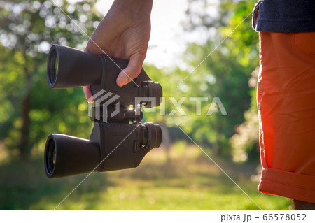 Male hiker looking through binoculars in forest Male hiker looking through binoculars in forest 66578052