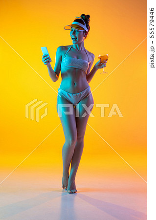 Fashion portrait of seductive girl in stylish swimwear posing on a bright yellow background. Summertime, beach season Fashion portrait of seductive girl in stylish swimwear posing on a bright yellow background. Summertime, beach season 66579446