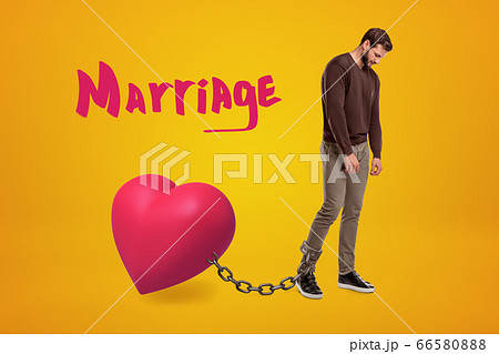 Young sad man wearing casual clothes chained to pink heart with 'Marriage' sign above on yellow background 66580888
