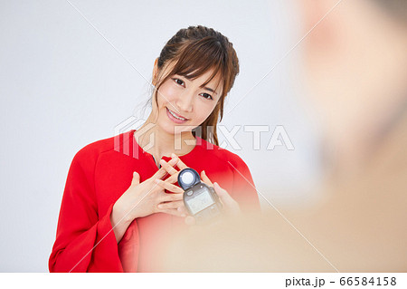 赤いコートを着た若い女性モデルとカメラマン 66584158