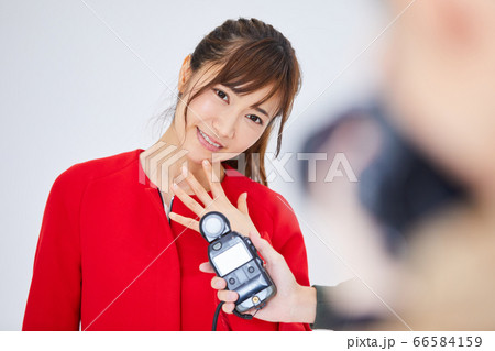 赤いコートを着た若い女性モデルとカメラマン 66584159