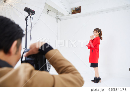 赤いコートを着た若い女性モデルとカメラマン 66584173