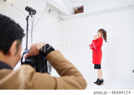 赤いコートを着た若い女性モデルとカメラマン 66584174