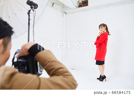 赤いコートを着た若い女性モデルとカメラマン 赤いコートを着た若い女性モデルとカメラマン 66584175