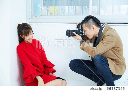 赤いコートを着た若い女性モデルとカメラマン 66587346