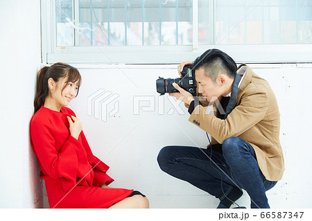 赤いコートを着た若い女性モデルとカメラマン 66587347