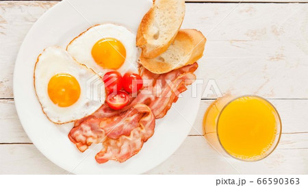 set breakfast,Ham,fried eggs,orange juice,Toast in white plate on wooden table 66590363
