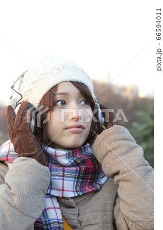 音楽を聴く冬服の女性 66594011