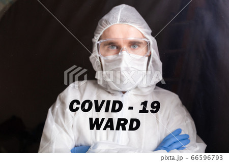 Man in protective suit and in protective medical mask showing stop gesture. Epidemiologist portrait. Stop coronavirus or covid-19 and the pandemic. Stay home. Quarantine concept. Man in protective suit and in protective medical mask showing stop gesture. Epidemiologist portrait. Stop coronavirus or covid-19 and the pandemic. Stay home. Quarantine concept. 66596793